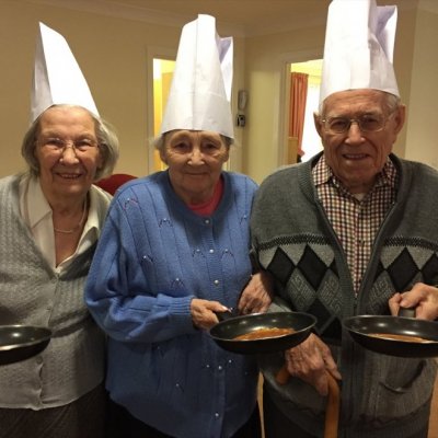 Three residents holding frying pan and pancake